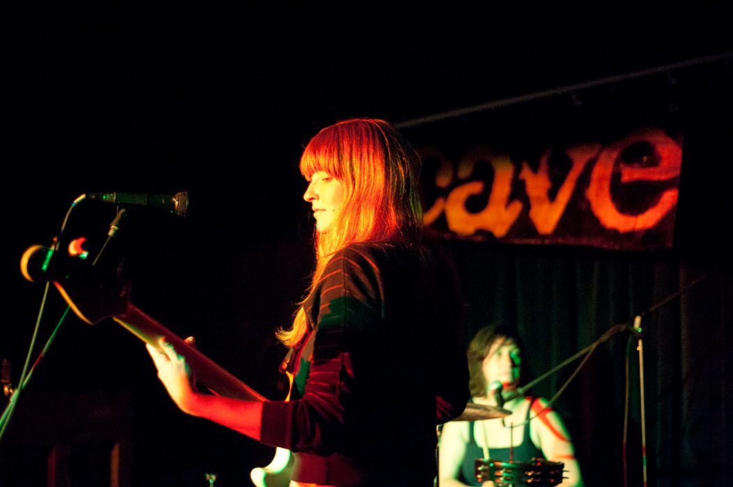 A performer plays guitar at the Cave