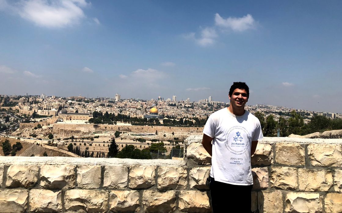 Aaron Forman stands against a stone wall overlooking Jerusalem