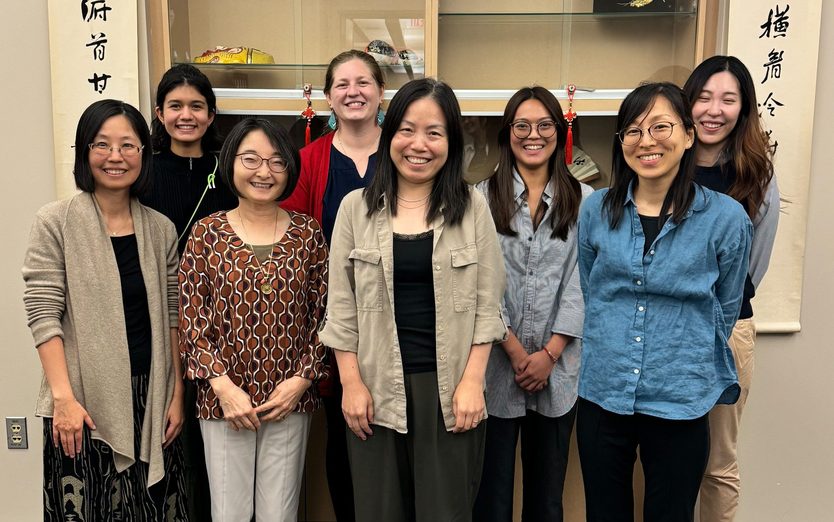 Faculty and Staff standing together in front of a display cabinet