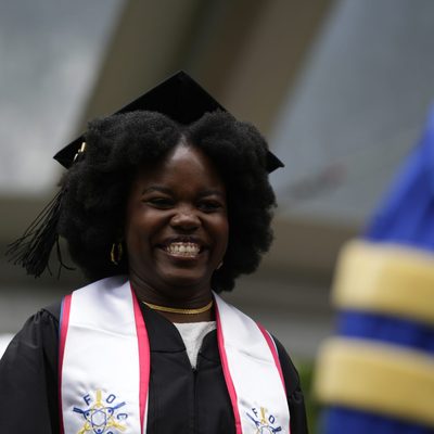 A student smiling as they receive their degree