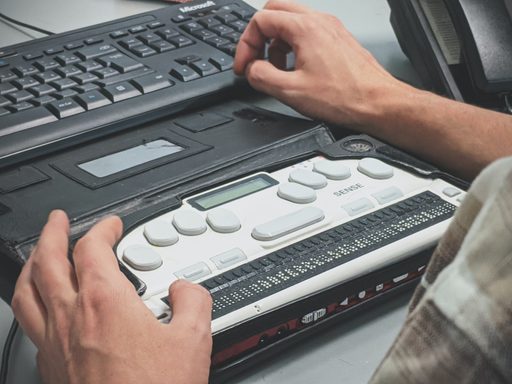 Person using a braille keyboard with a laptop
