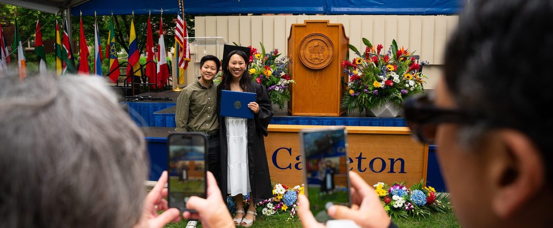 A student and her sibling pose for a photo at commencement