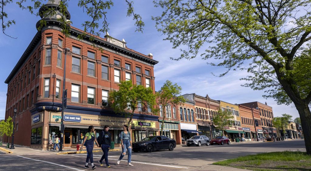 Three college students walk across a street in downtown Northfield 