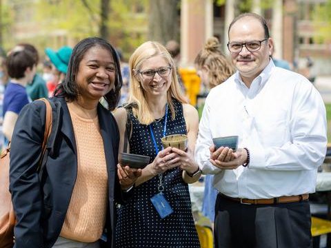 Three smiling Carleton staff members on the campus bald spot
