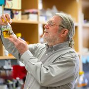 Brian Fox ’81 holds up a container of liquid in a lab.