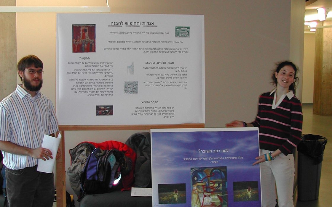 two students standing beside academic posters