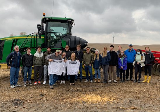 HIST100 students standing in front of farm equipment at Far Gaze Farms