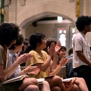 A student stands up in an applauding crowd at Honors Convo.