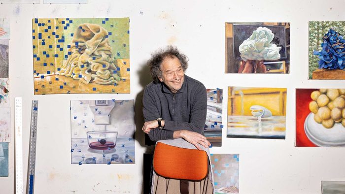 david lefkowitz leaning against a chair and smiling in front of student work