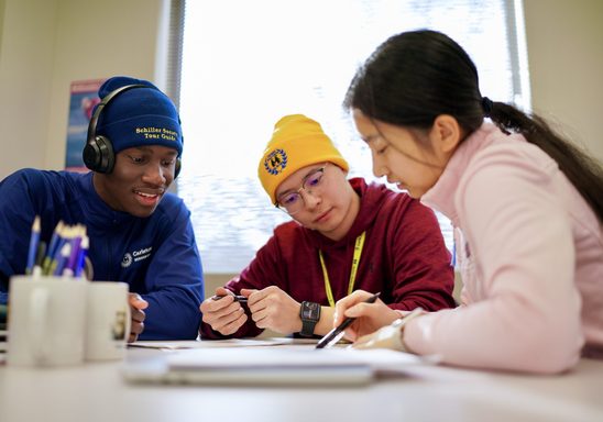 Three students work on a project over a table at the Math Skills Center