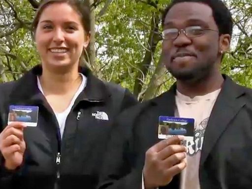 Two students standing outdoors holding up their OneCards