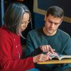 A professor and student look at a book together