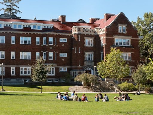 Photo of Burton Hall in the sunshine with an outdoor class taking place on the lawn.