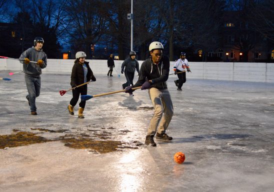 students play broomball at night.