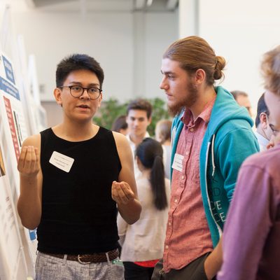 <p>Students have a conversation during a poster session for student research and externship positions</p>