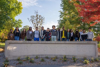 students posing next to Carleton sign