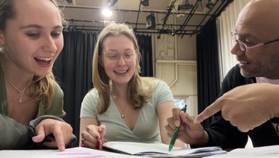 Two students looking at their scripts with a teacher