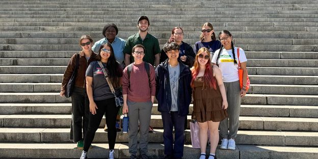 Ten people posing together on steps outdoors.