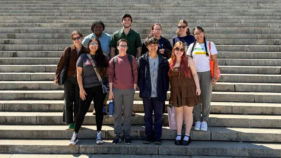 Ten people posing together on steps outdoors.
